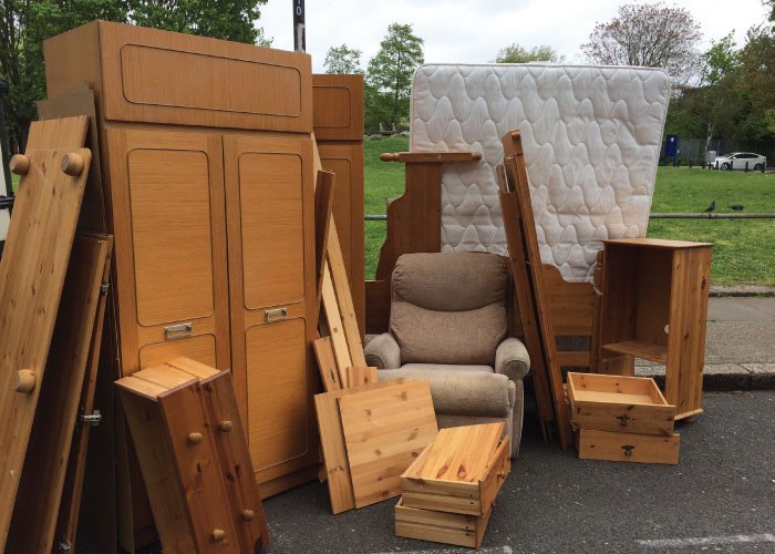 Wardrobes, a mattress and an armchair stacked at the kerb