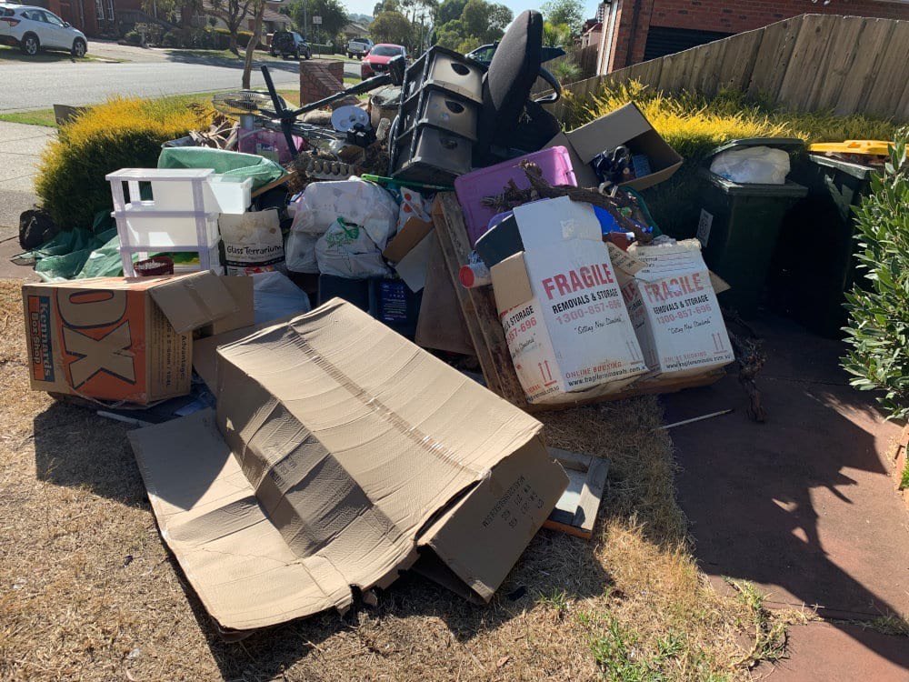 A front garden heaped with boxes, bags and household items waiting to be cleared